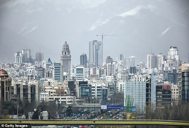 Im Bild die Skyline von Teheran im Iran mit Wolkenkratzern, Umweltverschmutzung und schneebedeckten Alborz-Bergen im Hintergrund.  Die Luftverschmutzung in Teheran wird als „ungesund“ beschrieben.
