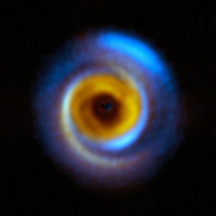 Dieses zusammengesetzte Bild zeigt die Planetenscheibe MWC 758, die sich etwa 500 Lichtjahre entfernt in der Taurus-Region befindet, wie sie mit zwei verschiedenen Einrichtungen beobachtet wurde.  Die gelbe Farbe stellt Infrarotbeobachtungen dar, die mit dem Instrument Spectro-Polarimetric High-contrast Exoplanet REsearch (SPHERE) am Very Large Telescope (VLT) der ESO gewonnen wurden.  Die blauen Bereiche hingegen entsprechen Beobachtungen, die mit dem Atacama Large Millimeter/submillimeter Array (ALMA) durchgeführt wurden.