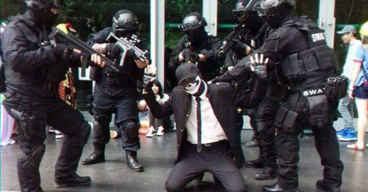 Ein Shadman-Cosplay auf den Knien, umgeben von einem SWAT-Team