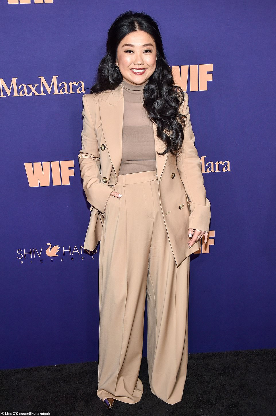 Sherry Cola looked elegant and chic in a tan trench blazer and wide-leg trousers. The Joy Ride actress teamed her suit with a sheer beige turtleneck top and pointed-toe boots