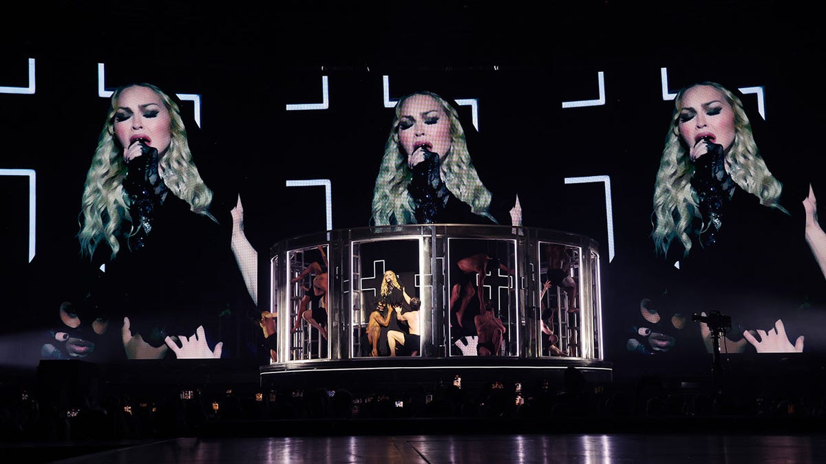 Madonna singt auf der Bühne, ihr Gesicht ist über ihr projiziert
