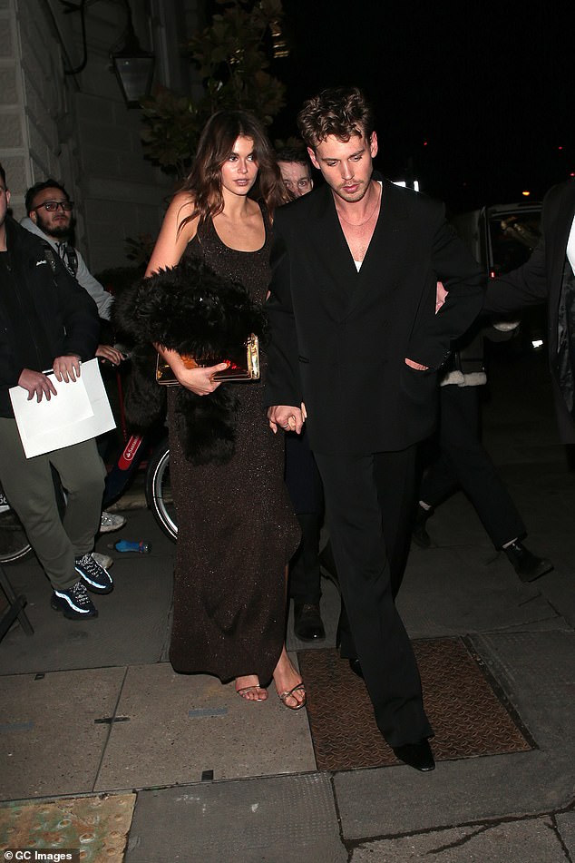 Kaia trug ein ärmelloses schwarzes Maxikleid und einen schicken Mantel in der Hand, während sie mit Austin Händchen hielt;  abgebildet am 15. Februar in London