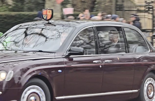 King Charles III is pictured waving to cheering royal fans from his car in London yesterday