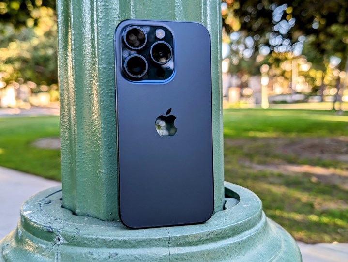 Blue Titanium iPhone 15 Pro leaning on park lamp post.