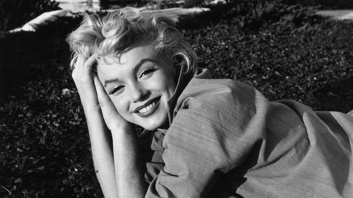 Marilyn Monroe stützte sich auf ihre Hände und lächelte