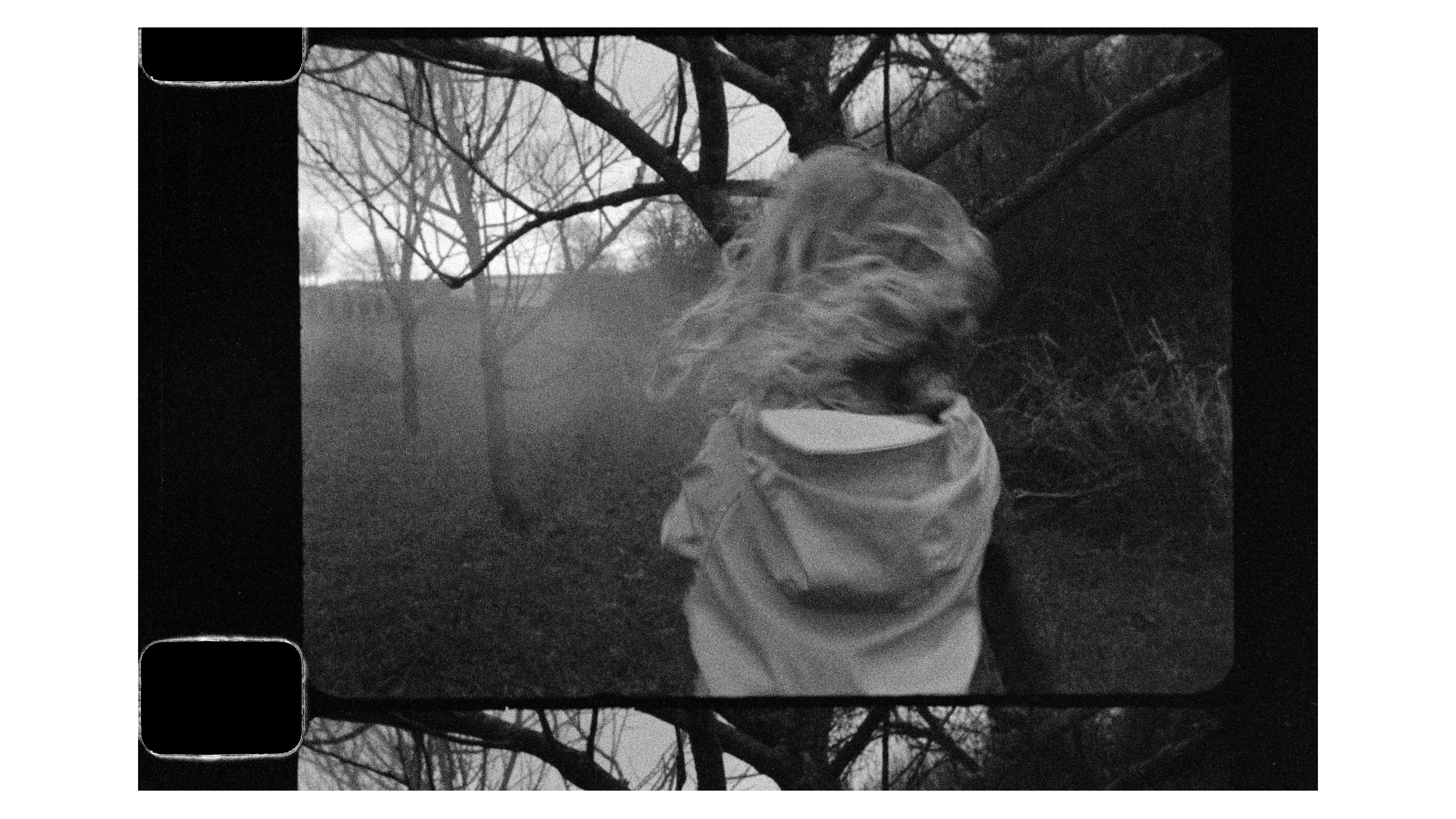 Auf einem Schwarz-Weiß-Foto läuft ein junges Mädchen durch ein Waldgebiet