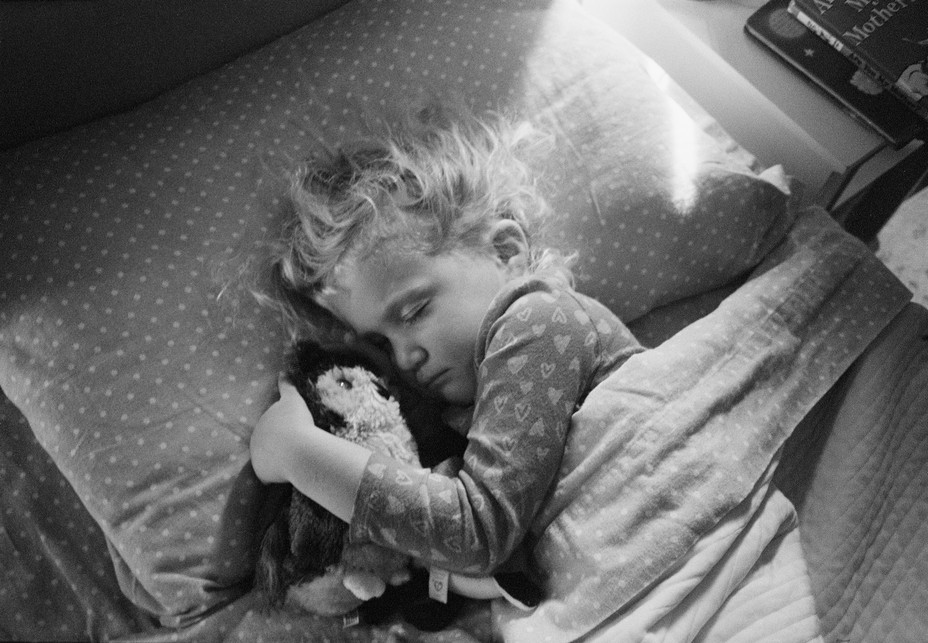 Ein Kind umklammert eine ausgestopfte Eule in seinem Bett