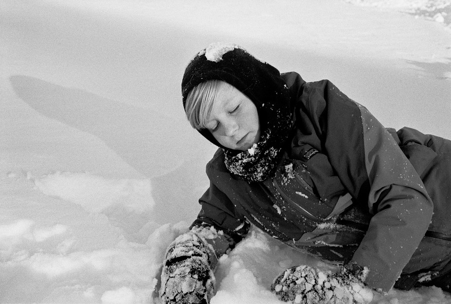 SW-Bild eines Jungen, der im Schnee liegt