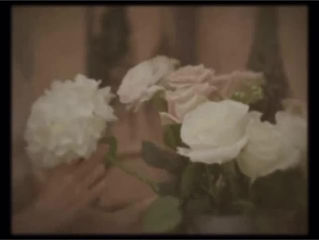 Das Video beginnt mit einem verwaschenen Video einer Frau, die weiße und rosa Pastellblumen arrangiert