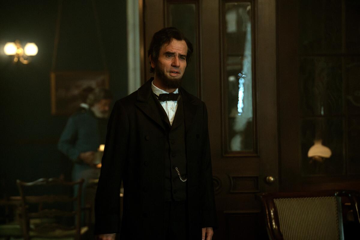 Hamish Linklater als Abraham Lincoln mit Bart und schwarzem Anzug und Fliege.