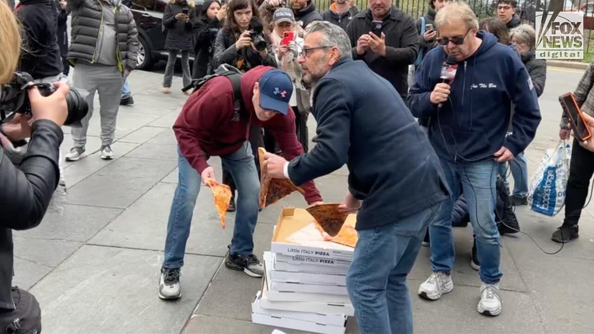 Scott LoBaido holt mit einem anderen Demonstranten Pizza ab