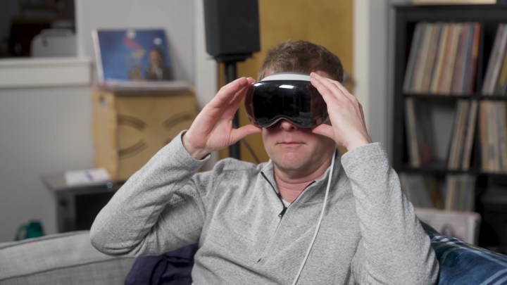 A man adjusts an Apple Vision Pro headset over his eyes. 
