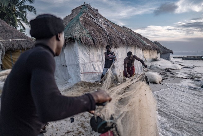 Fischer bereiten ihre Netze vor, während sich eine steigende Flut den umliegenden Häusern auf der Insel Nyangai nähert. 
