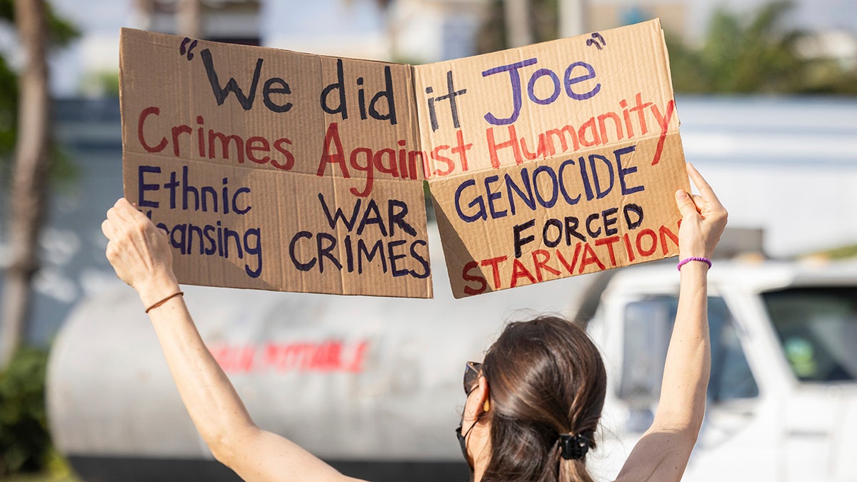 Demonstrant aus San Juan hält ein Schild hoch, auf dem er Biden und Harris verurteilt "Kriegsverbrechen."
