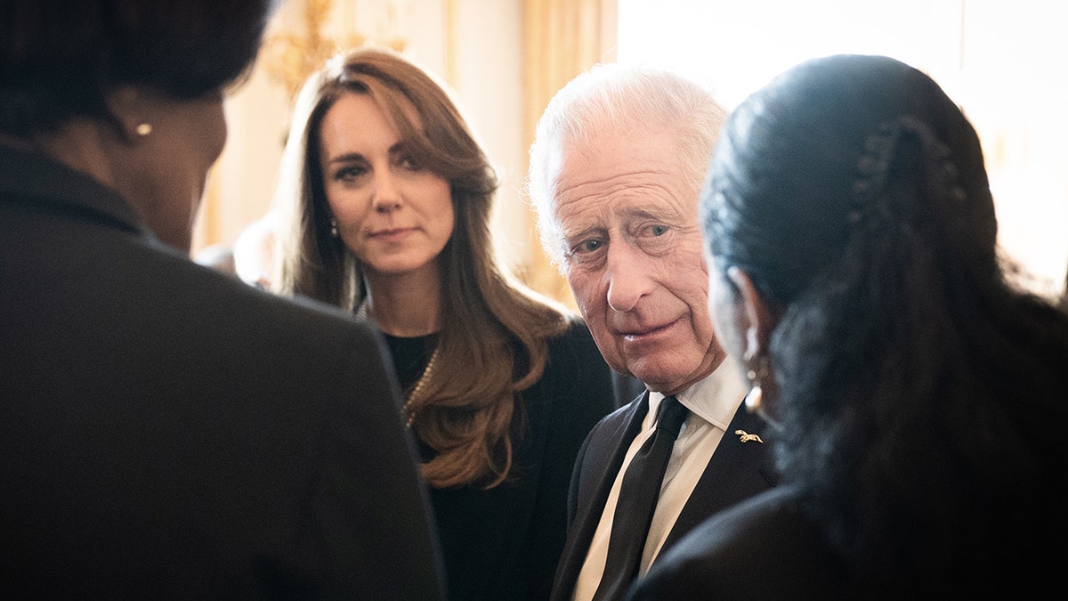 Kate Middleton in Schwarz blickt König Karl III. in schwarzem Anzug und Krawatte an 
