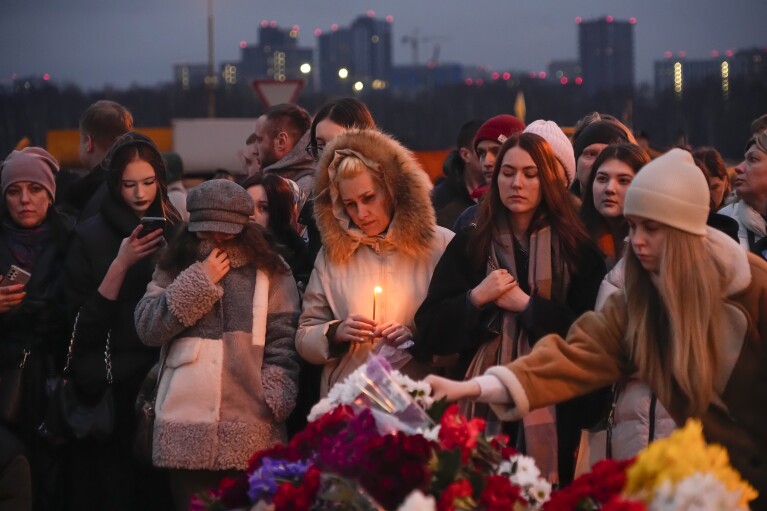 Am Samstag, den 23. März 2024, legen Menschen neben dem Crocus-Rathaus am westlichen Rand von Moskau, Russland, Blumen nieder und zünden Kerzen an. (AP Photo/Alexander Zemlianichenko)