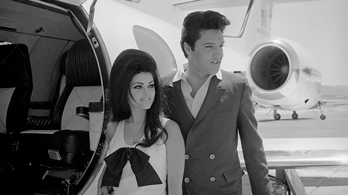 Schwarzweißfoto von Priscilla Presley und Elvis Presley, die neben dem Flugzeug stehen