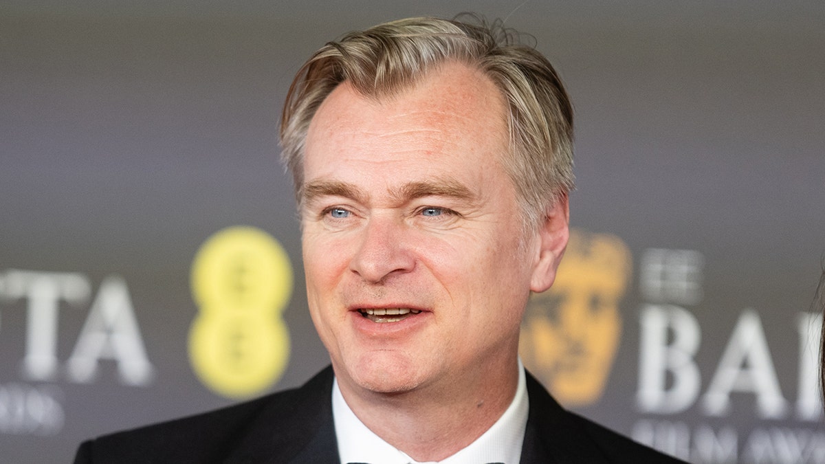 Christopher Nolan blickt in einem schwarzen Anzug auf den Teppich der BAFTAS