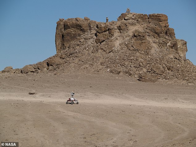Wissenschaftler nutzen die Insel Devon – auf der Erde auch Mars genannt –, um zu erforschen, wie Menschen andere Planeten besiedeln könnten.  Das Epizentrum ihrer Arbeit ist eine der höchstgelegenen „Einschlagstrukturen“ der Erde: der Haughton-Krater.  Oben ist ein NASA-Rover zu sehen, der das jenseitige Gelände des Kraters erkundet