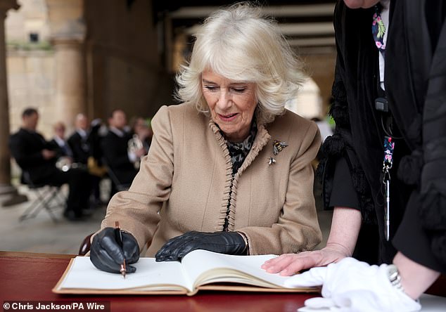Camilla signs the visitors' book at the Old Market Hall during her trip to Shrewsbury today