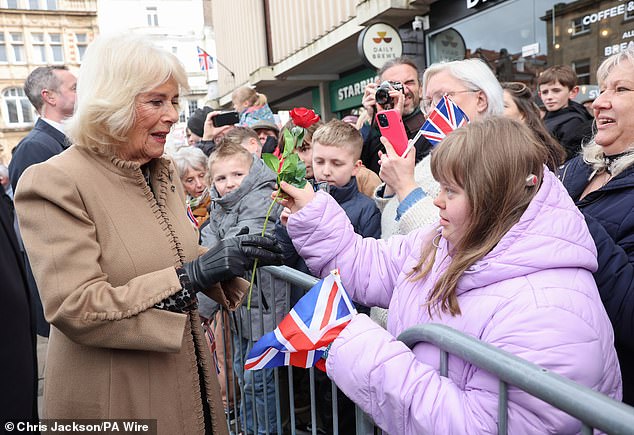 Queen Camilla smiles after receiving a red rose from Abi Crighton in Shrewsbury today