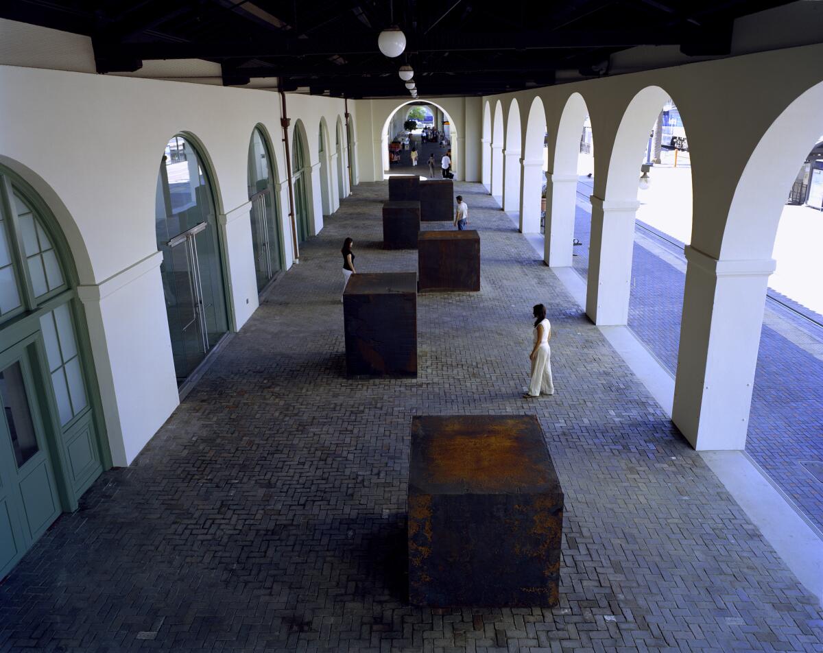 Sechs würfelförmige Stahlkonstruktionen sind in einem Korridor mit Bögen versetzt angeordnet.