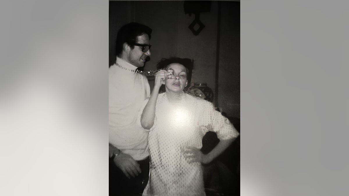 John Meyer steht neben Judy Garland, während sie ihr Augen-Make-up aufträgt