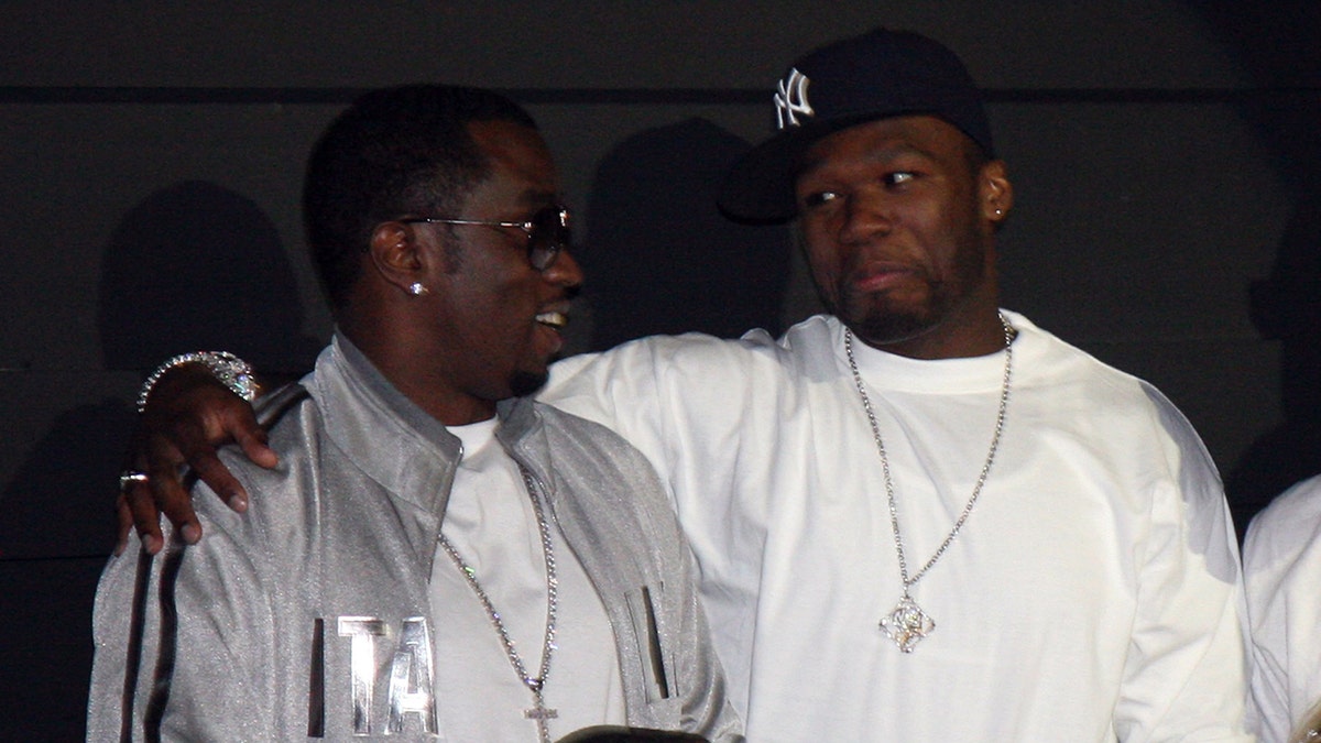 50 Cent in einem Yankees-Fan und weißem Hemd legt seinen Arm um P Diddy in einer silbernen Jacke und Sonnenbrille in Las Vegas