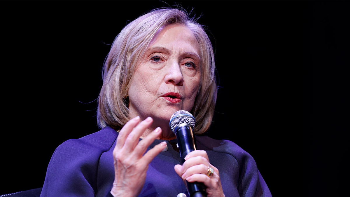Hillary Clinton hält ein Mikrofon vor schwarzem Hintergrund
