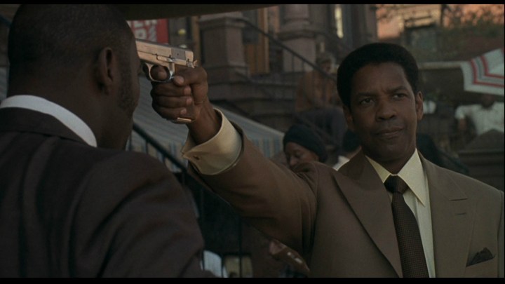 Denzel Washington hält in „American Gangster“ eine Waffe in der Hand.