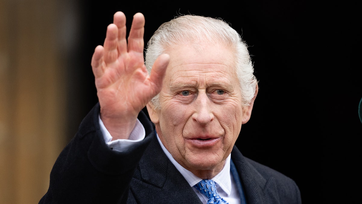König Charles im schwarzen Anzug und mit blauer Krawatte winkt an Ostern der Menge vor Windsor Castle zu