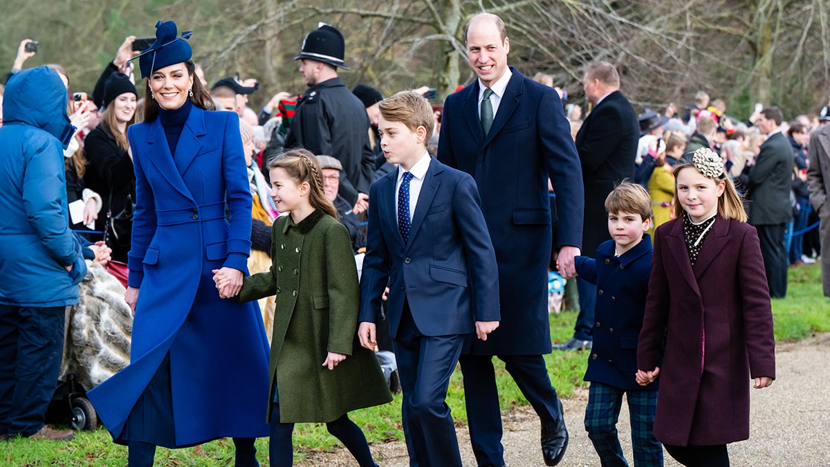 Prinzessin Catherine in königsblauer Jacke und Hut hält Prinzessin Charlottes Hand, während sie neben Prinz William, Prinz George und Louis und Mia Tindall zum Weihnachtsgottesdienst geht