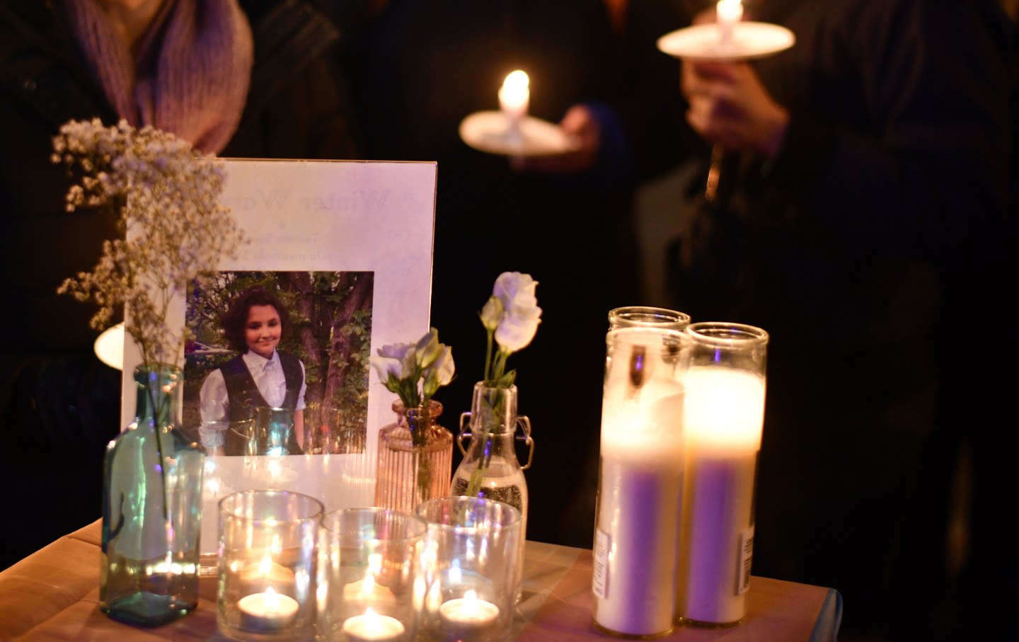 Foto von Nex Benedict auf einem Tisch neben Kerzen und Blumen
