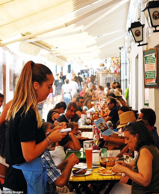 Das Aktenfoto zeigt eine Kellnerin, die während einer geschäftigen Mittagszeit eine Bestellung auf einem Block auf der Terrasse einer Tapas-Bar in Conil de la Frontera in der Nähe von Cádiz entgegennimmt