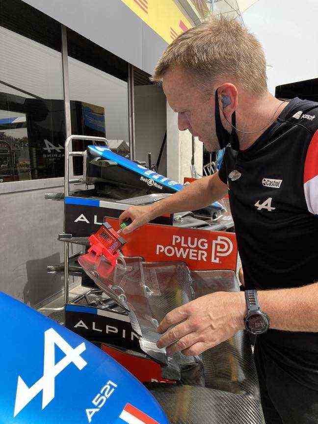 An Alpine mechanic checking the degree of tilt of the front wing.