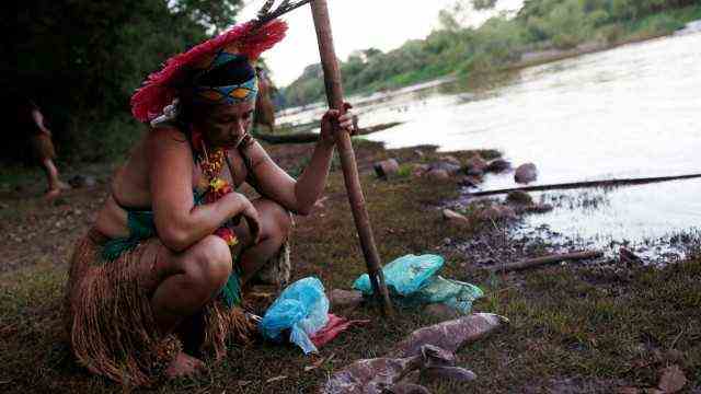 An Indigenous woman looks at dead fish near Paraopeba river in Sao Joaquim de Bicas