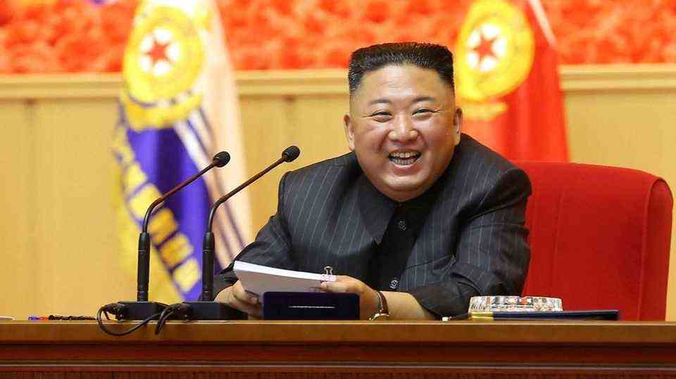 North Kria's dictator Kim Jong And sits at a lectern and laughs