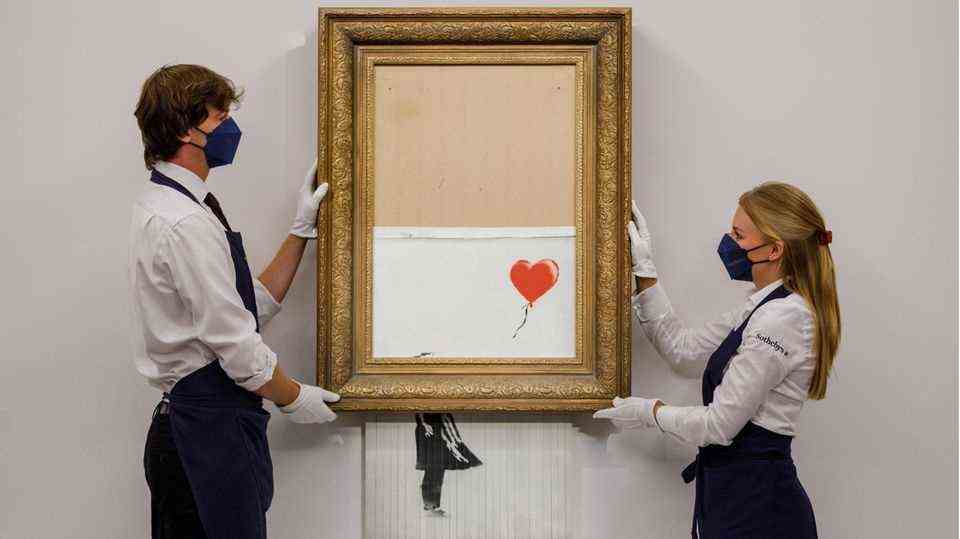 Sotheby's employees show Banksy's shredded Girl with Balloon