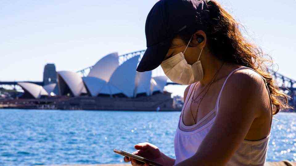 Während des neuen Lockdowns in Sydney spaziert eine Frau mit Mobiltelefon im Royal Botanical Garden