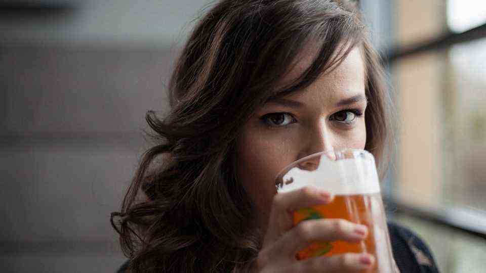 A young woman is drinking beer