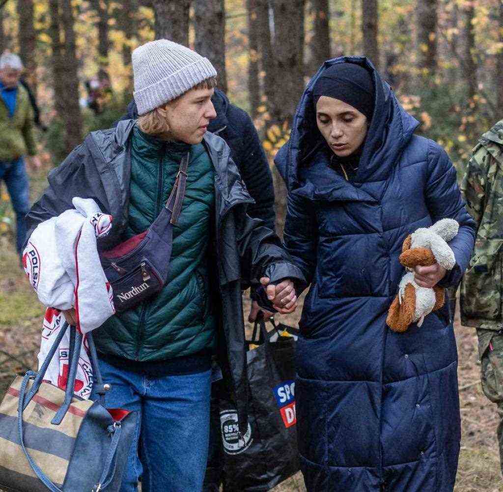 Eine Flüchtlingshelferin (l.) begleitet eine syrische Familie im Wald nahe Kleszczele. Hinten rechts: eine polnische Grenzschutz-Mitarbeiterin