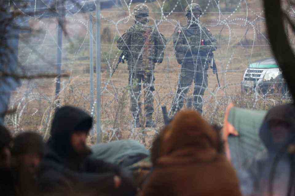 Polish military keeps an eye on the refugees behind the barbed wire fence on the Belarusian side of the border.