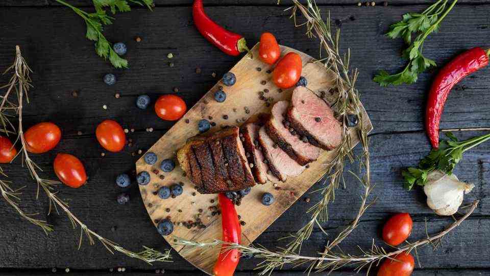Christmas roast with blueberries, tomatoes, peppers and rosemary served on a wooden board