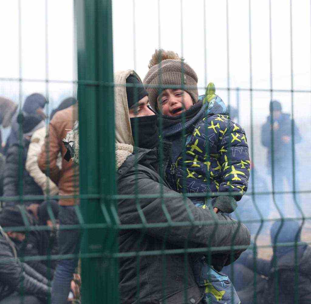A child cries as migrants gather at the border crossing trying to cross the Belarusian-Polish border in the Grodno region