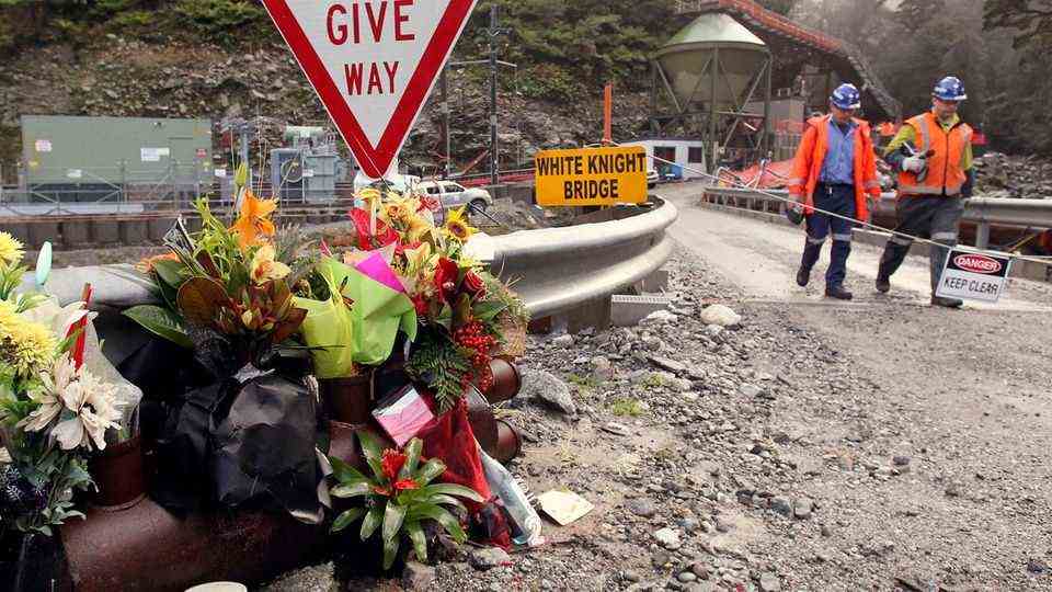 Arbeiter gehen an Blumen für die Opfer der Minenexplosion in der Pike-River-Mine vorbei (Archivbild)
