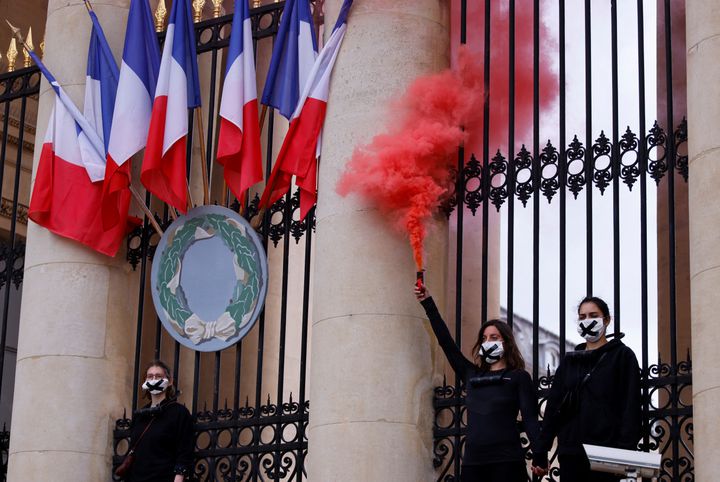 Des militantes du mouvement Extinction Rebellion accrochées aux grilles de l'Assemblée nationale, à Paris, le 4 mai 2021.&nbsp; (THOMAS SAMSON / AFP)