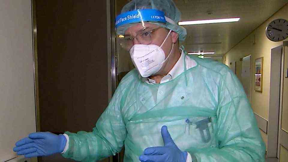 A doctor in protective clothing stands in a hospital corridor.