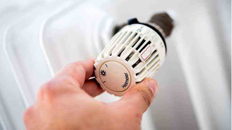 A hand turns the thermostat of a heater