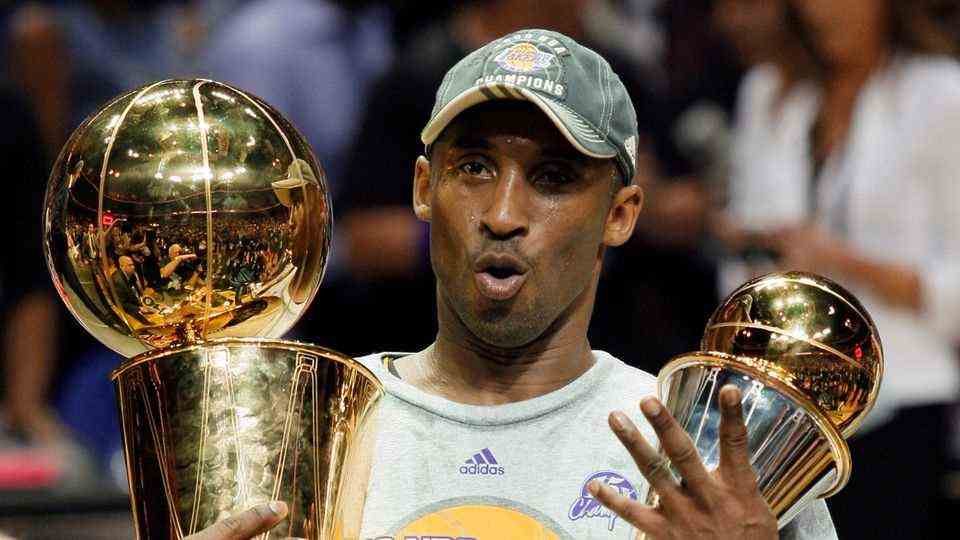 Kobe Bryant holding the Larry O'Brien Championship Trophy and MVP Finals Trophy