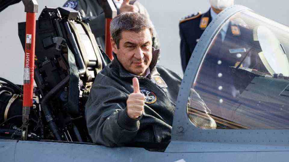 Markus Söder makes one "Thumbs up"-Gest out of the cockpit of a Eurofighter jet.